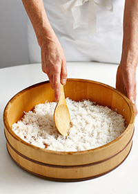 Spread hot rice into a large wooden bowl